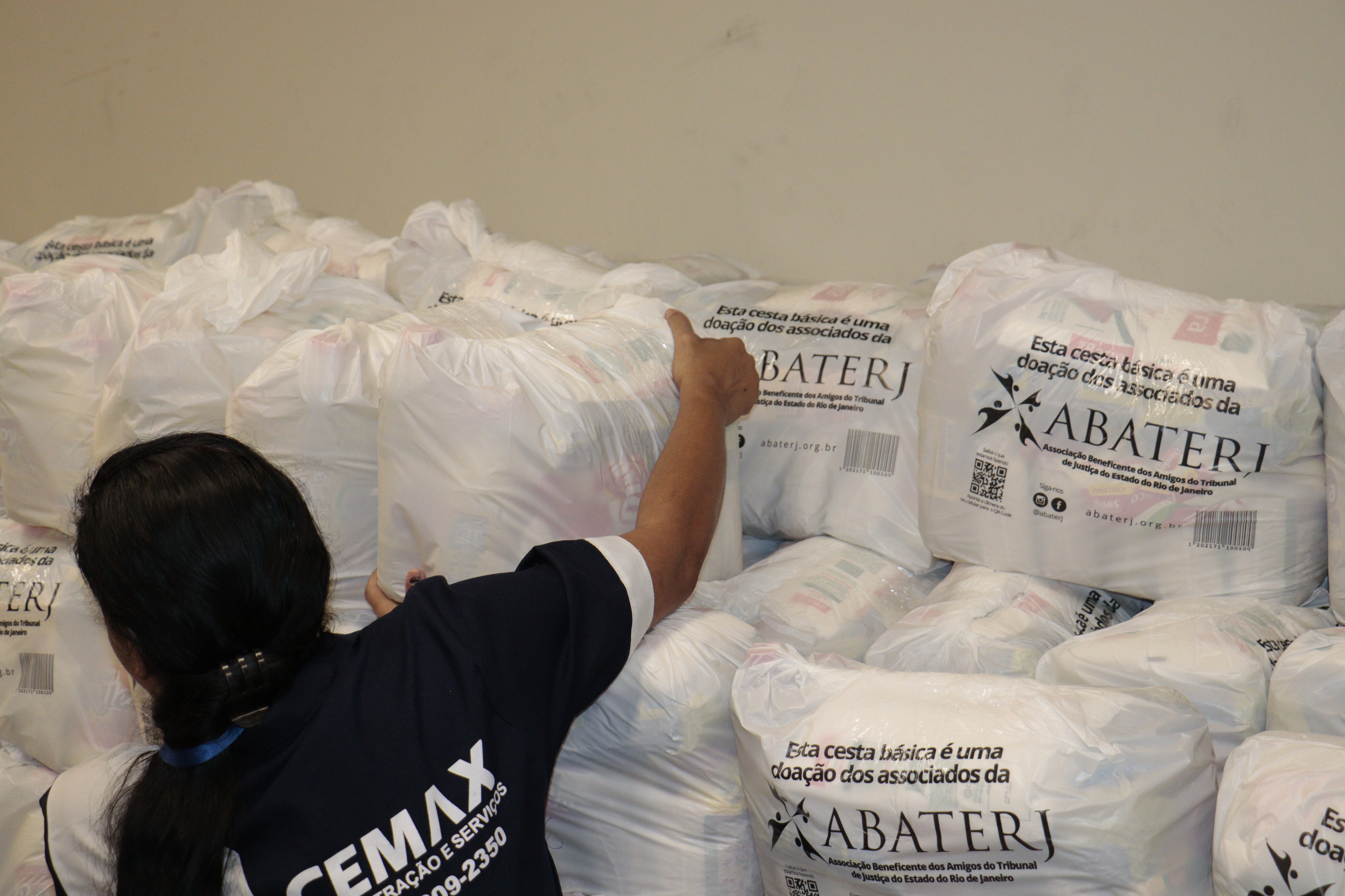 Mulher de costas pegando uma cesta básica.