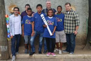 Acompanhadas pelo juiz Luiz Henrique Alves, quatro crianças exibem orgulhosas a tocha olímpica