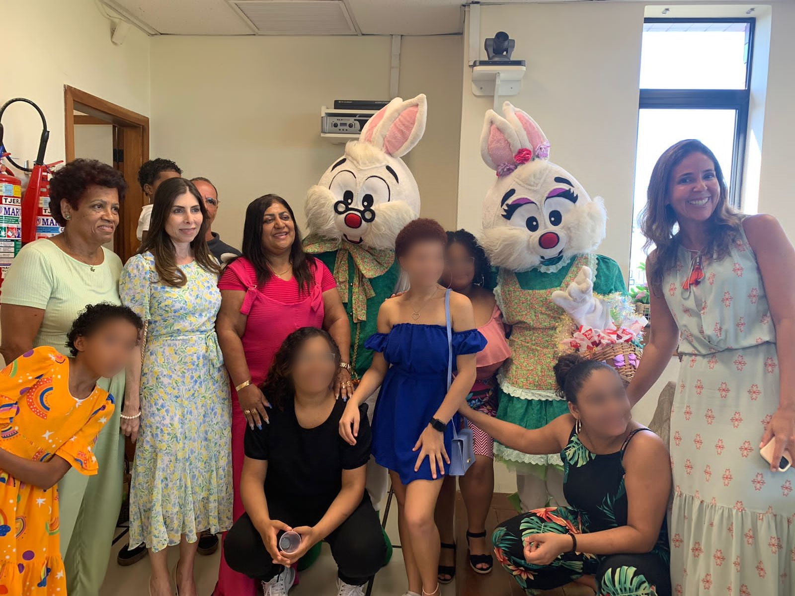 crianças, assistentes e a magistrada posam para foto com animadores fantasiados de coelho