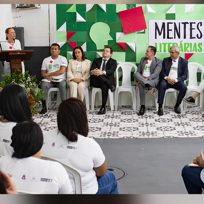A foto apresenta as internas de costas e as autoridades sentadas de frente com a 2ª vice-presidente do TJRJ, desembargadora Maria Angélica, em pé discursando.