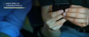 #ParaTodosVerem: Acima, no canto esquerdo, o título “EMENTÁRIO DE JURISPRUDÊNCIA”. “À esquerda, um homem de camisa de manga comprida azul olha para um celular que está nas mãos de outro homem, que veste uma camisa de manga curta preta e calça jeans, à direita.”