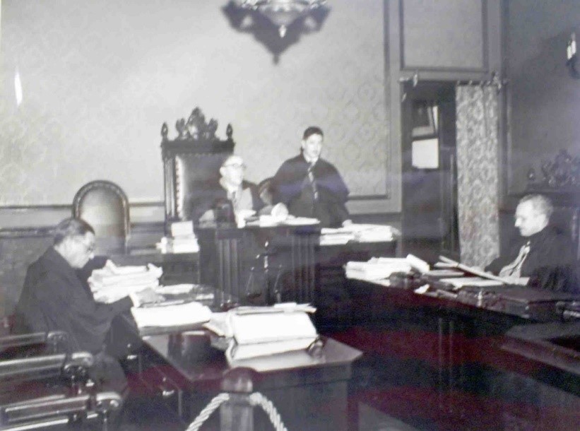 Fotografia em preto e branco do desembargador Antonio Vieira Braga e outros, na sala da Câmara Isolada.