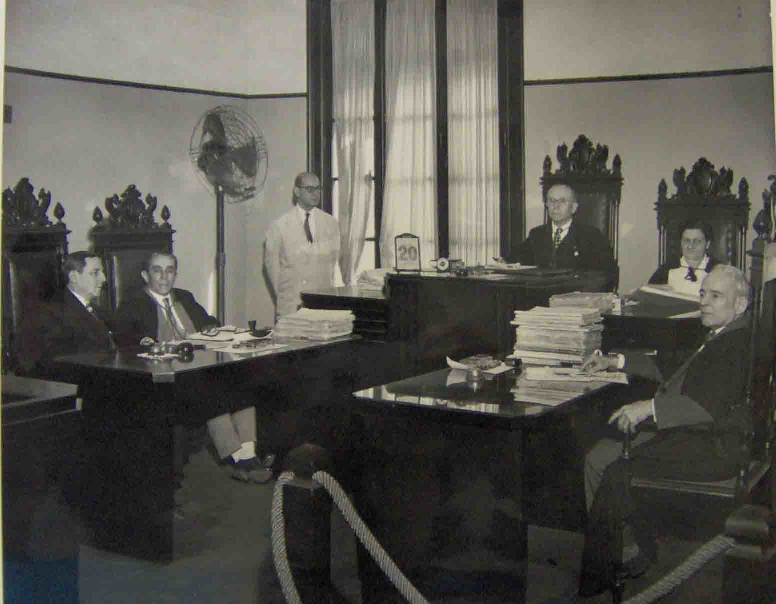Fotografia em preto e branco do desembargador Eduardo de Souza Santos e outros, na sala da Câmara Isolada.