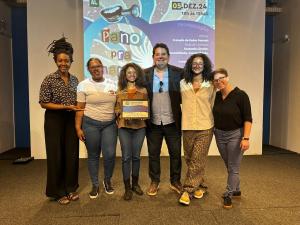 Na foto, da esquerda para a direita: Nayla Oliveira, da instituição MUHCAB; Lívia Barbosa Prado, integrante da Agenda Cultural do Museu da Justiça; Sérgio Ricardo Von Sydol, Chefe de Serviço da Agenda Cultural, que compareceu no evento em representação da diretora do Museu da Justiça, Silea Macieira; Maria Júlia Barbosa Torres e Sara dos Santos Machado, ambas integrantes da Agenda Cultural do Museu da Justiça.