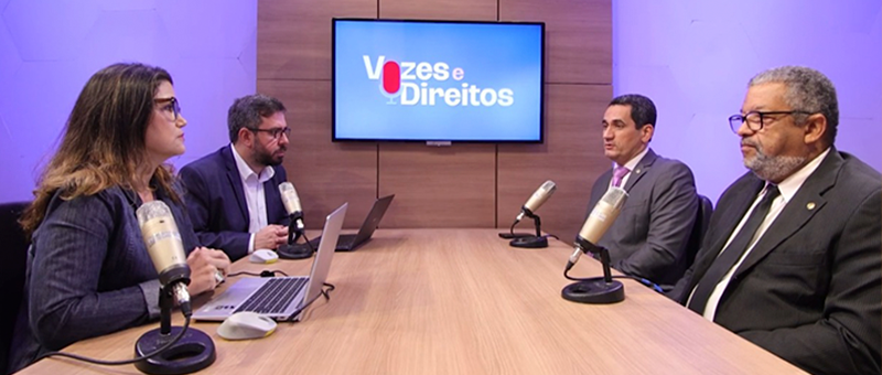 Imagem do estúdio onde é gravado o podcast. Ao lado esquerdo, os jornalistas Luiz Felipe Barreto e Simone Lamim. Ao lado direito, o juiz Sérgio Luiz Ribeiro e Carlos Roberto Laudelino