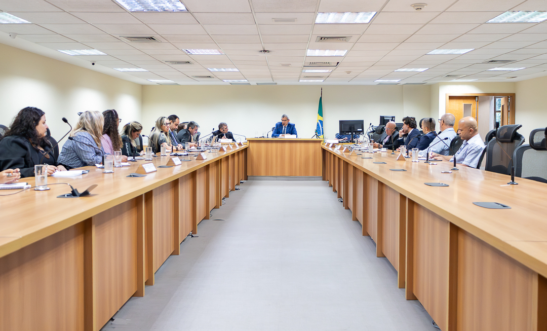 Foto da sala de reunião com mesa em formato de "U" com o desembargador Marcelo Anátocles no centro e os demais participantes nas laterais.