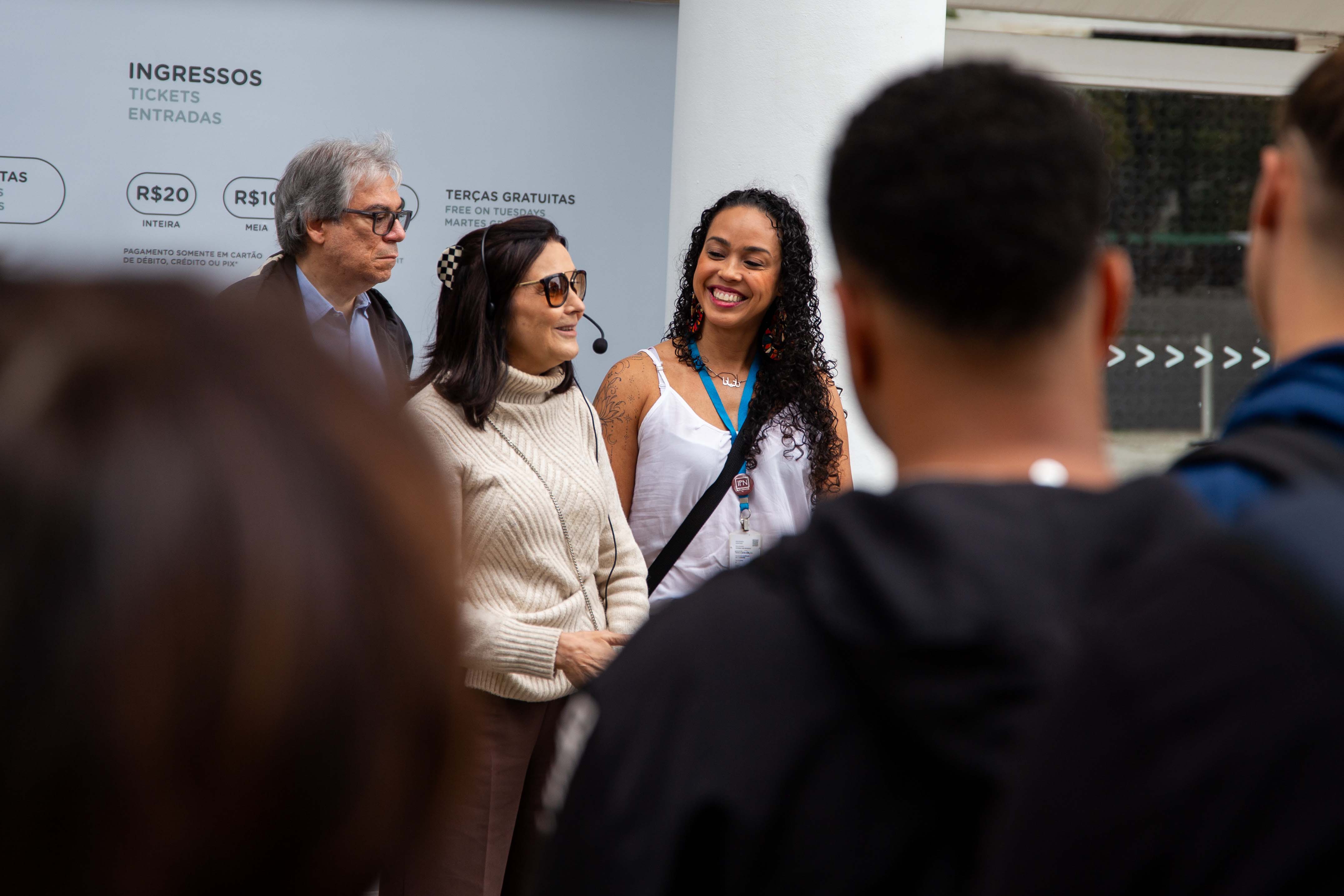 Três pessoas - um homem e duas mulheres - no centro falam com o restante do grupo