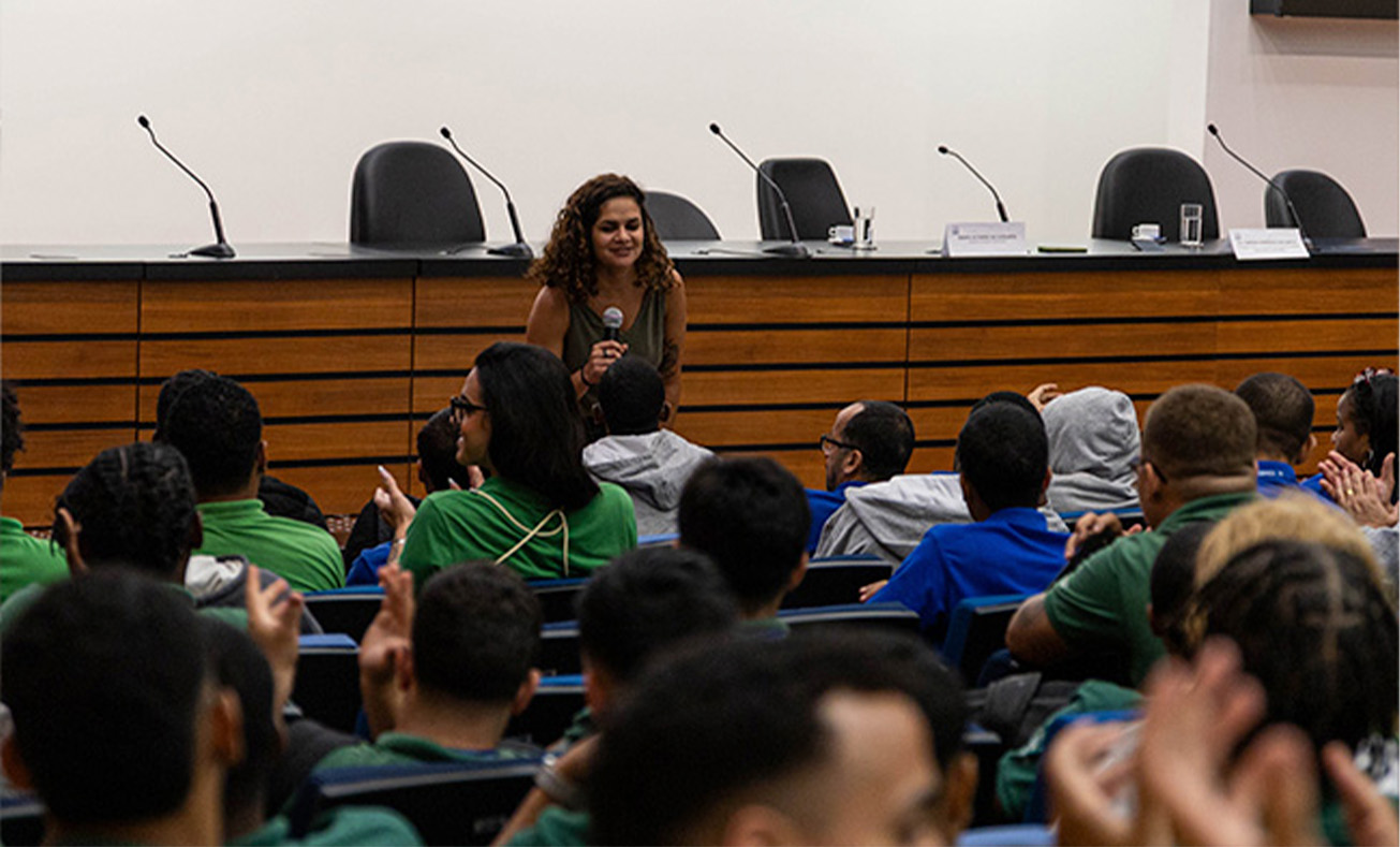 Imagem da psicóloga Amanda Rodrigues durante palestra sobre saúde mental para jovens de projetos sociais no auditório Desembargador Antônio Carlos Amorim