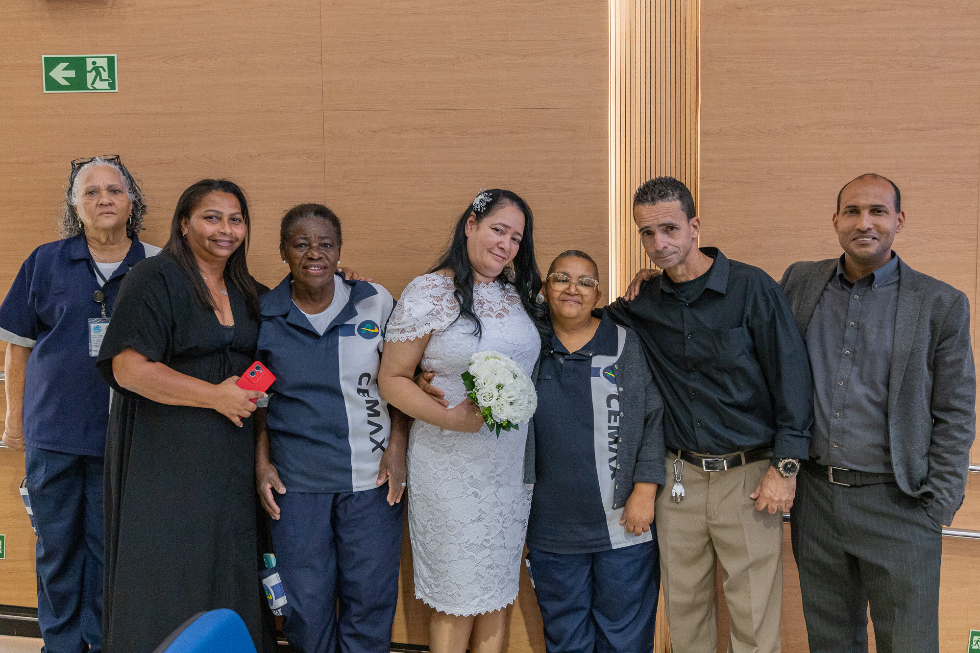 Foto posado do casal Simone e Flavio abraçados com familiares e colegas do TJRJ