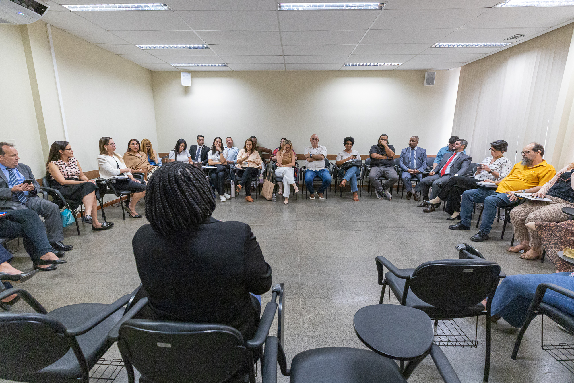 Imagem de uma sala com pessoas sentadas em cadeiras formando uma roda 