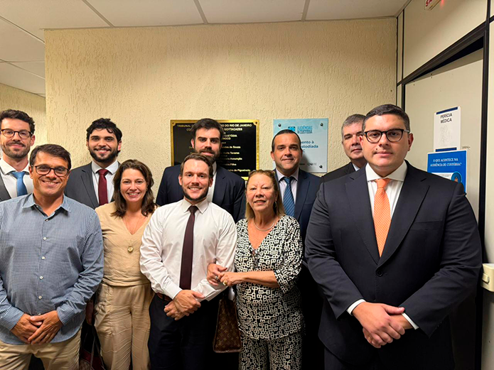 A imagem mostra 10 pessoas posando para a foto em um ambiente fechado. Na frente, duas mulheres e três homens e, atrás, cinco homens. 