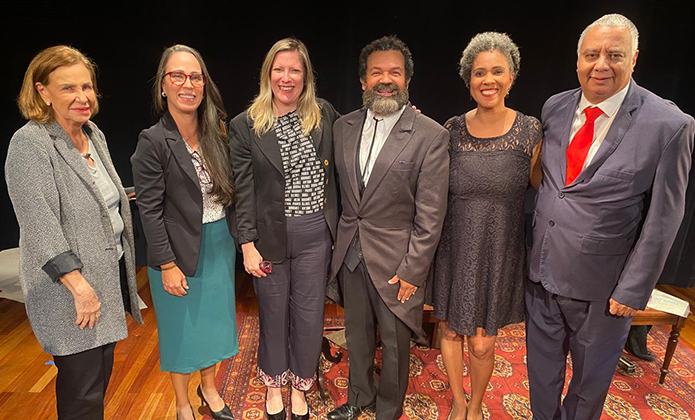 A imagem mostra seis pessoas no palco da Sala Multiuso (quatro mulheres e dois homens)