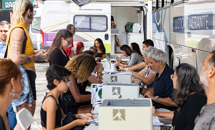 Magistrados, servidores e colaboradores fazem o atendimento de pessoas trans em mesas junto ao ônibus do Justiça Itinerante na Central do Brasil