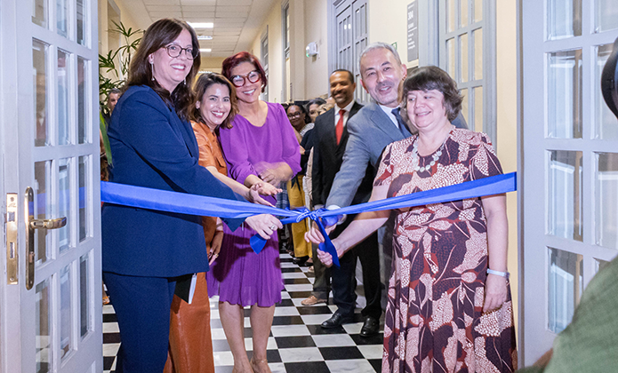 Cinco pessoas (quatro mulheres e um homem) aparecem em destaque descerrando a fita para abertura da exposição 