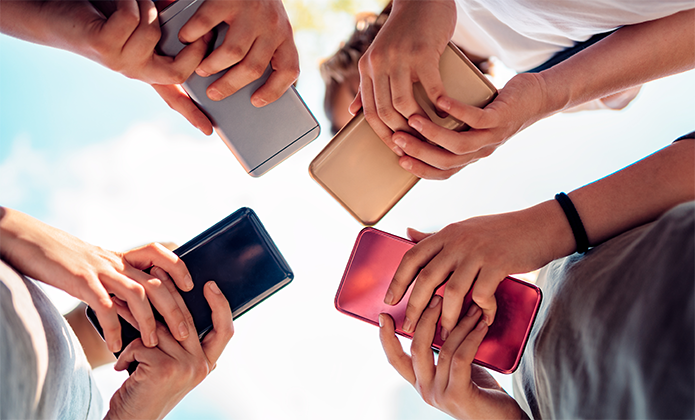 #ParaTodosVerem: Imagem vista de baixo mostra várias mãos segurando celulares coloridos, formando um círculo contra o céu claro.
