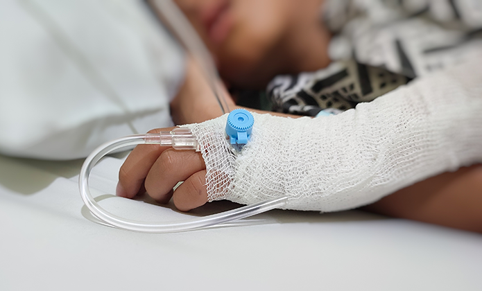 #ParaTodosVerem: Imagem mostra uma pessoa deitada em cama hospitalar, com mão enfaixada e acesso intravenoso conectado, sugerindo internação.